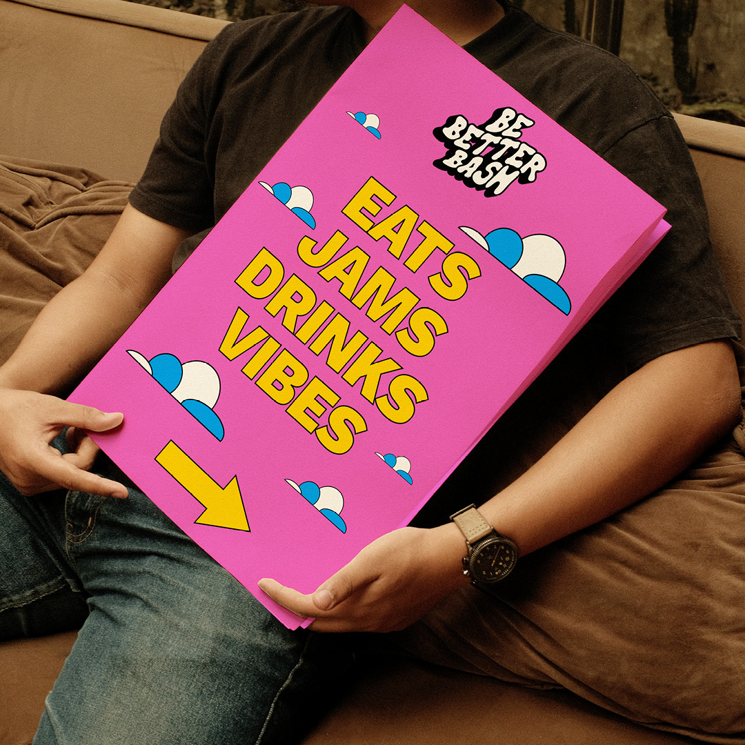 Person holding an 'Eats, jams, drinks, vibes' event poster