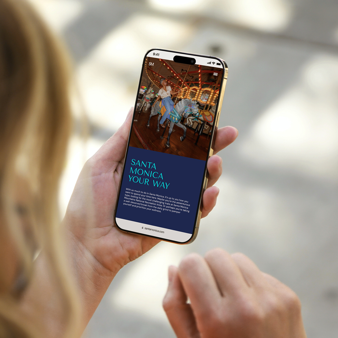 Hand holding a phone showing the Santa Monica website