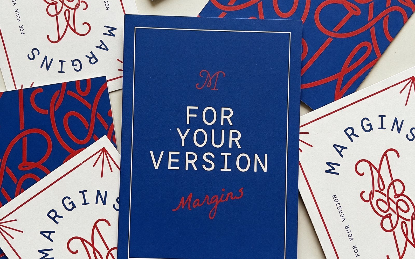 Flat lay of Margins cards in royal blue, red and cream, with a blue For Your Version card at the center and red looping pattern cards around it